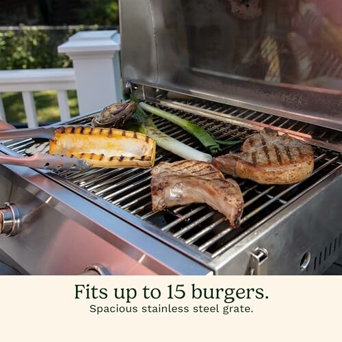 Grill with vegetables and meat on a stainless steel grate.