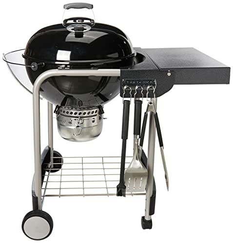 A Charcoal grill with attached table and cooking tools.